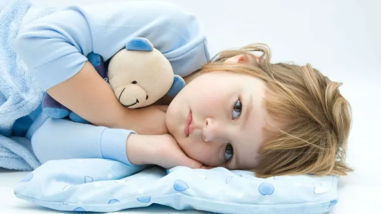 Bambina sveglia nel suo lettino con un orsetto
