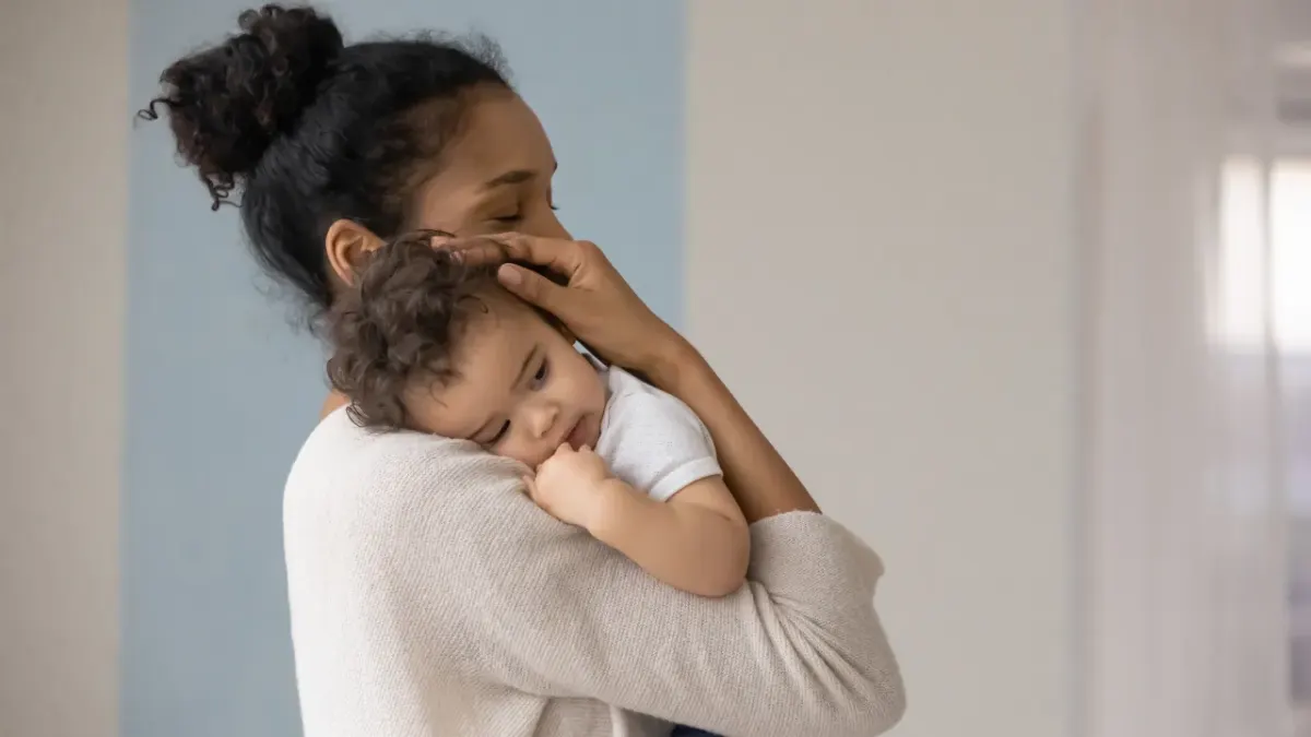 Una madre in piedi di notte, con il bambino addormentato in braccio